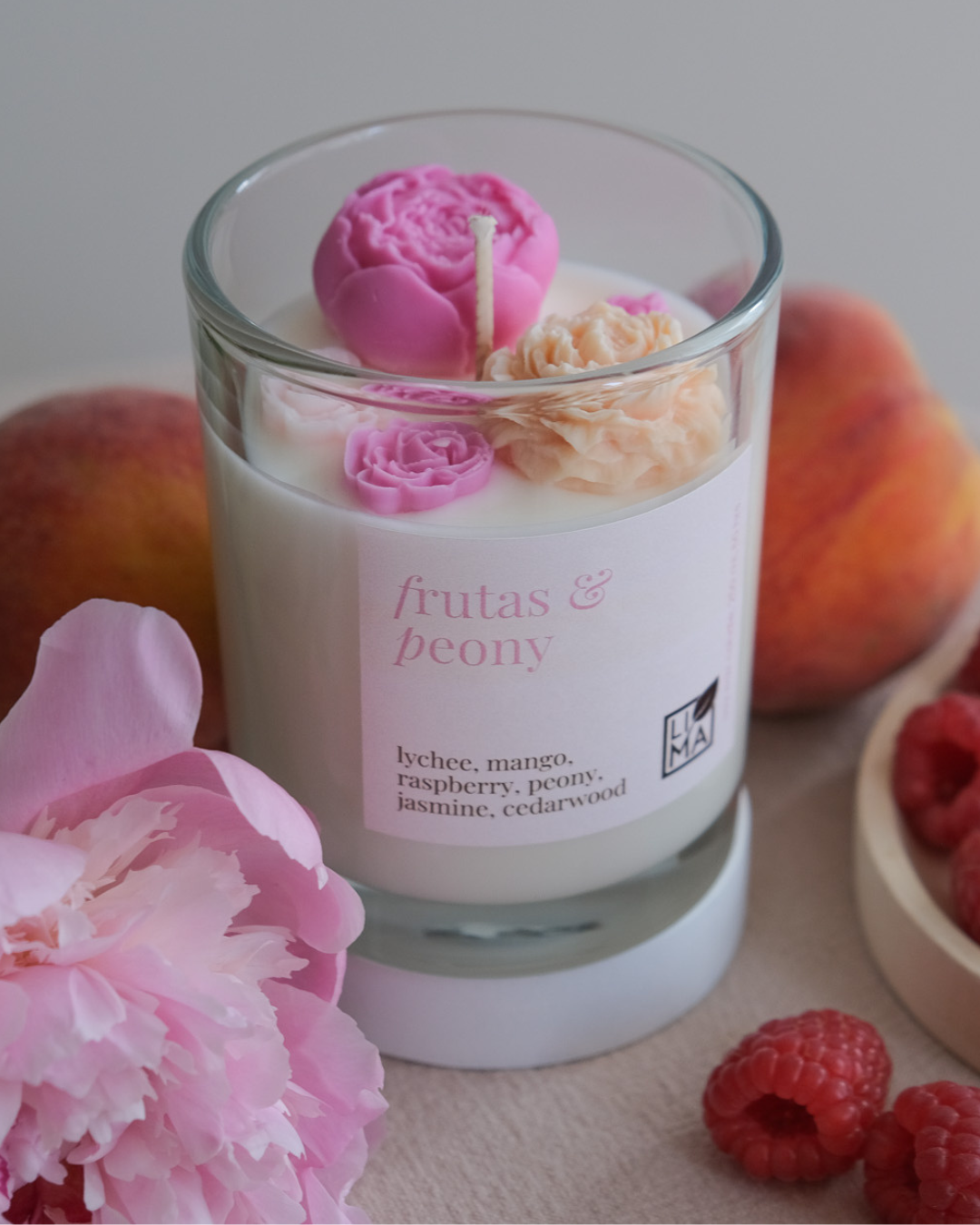 Blumige Kerze umgeben von Früchten und Pfingstrose